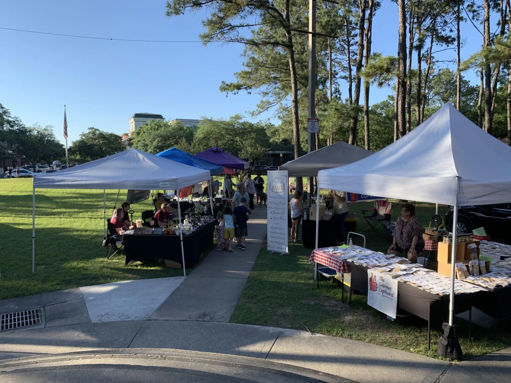 Visitors talking with food vendors beside the market path